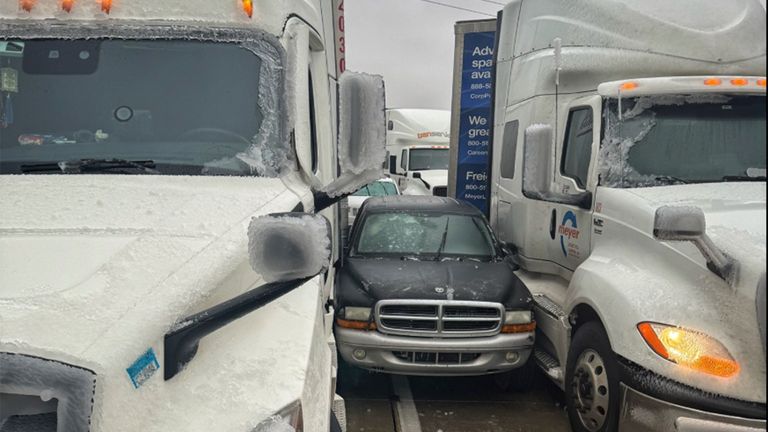 A car wedged between two trucks after sliding in icy conditions. Pic: Kansas Highway Patrol/AP