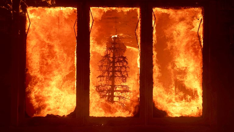 The Palisades Fire burns a Christmas tree inside a residence in the Pacific Palisades neighborhood of Los Angeles, Tuesday, Jan. 7, 2025. (AP Photo/Ethan Swope)