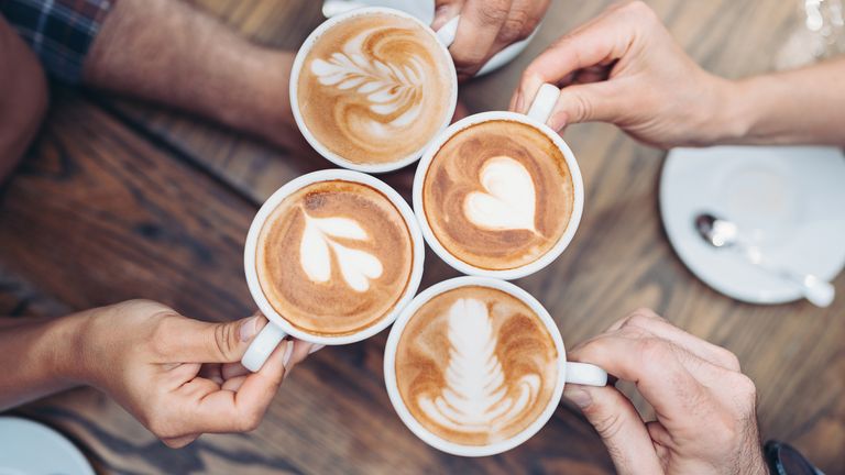 Empat orang sedang memegang cangkir kopi latte dengan latte art beragam di atasnya.