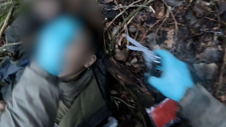 A Ukrainian soldier takes forensic samples from the body of a North Korean on the battlefield