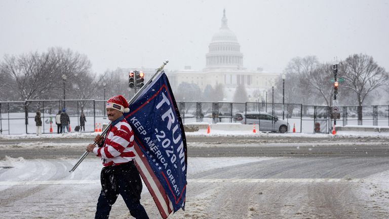 A supporter of U.S. President-elect Donald Trump holds flags and banners near the U.S. Capitol, on the day of a joint session of the Congress to certify Donald Trump's election, as a winter storm that brought snow, ice and freezing temperatures to a broad swath of the U.S. arrived, in Washington, U.S. January 6, 2025. REUTERS/Marko Djurica

