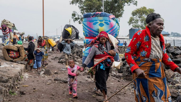 Fleeing families with mattresses strapped to their backs made their way through Goma. Pic: Reuters