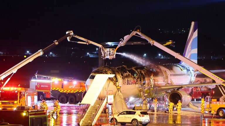 Firefighters work to extinguish a fire on an Air Busan airplane at Gimhae International Airport in Busan, South Korea.
Pic:Yonhap/AP