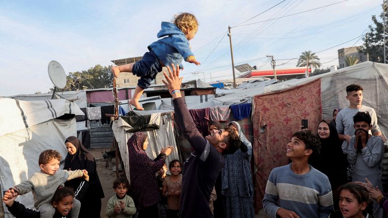 A man throws a child into the air as displaced Palestinians celebrate at a tent camp following a ceasefire between Israel and Hamas, in Deir Al-Balah in the central Gaza Strip, January 19, 2025. Pic: Reuters