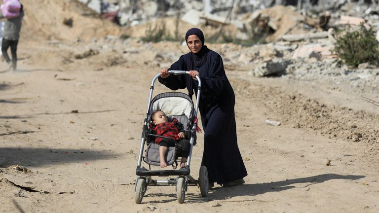 A Palestinian woman pushes a child in a stroller after returning to her devastated neighborhood, following a ceasefire between Israel and Hamas, in Jabalia in the northern Gaza Strip, January 19, 2025. REUTERS/Dawoud Abu Alkas

