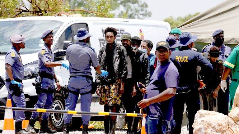 Miners are escorted by police officers after being rescued from below ground in an abandoned gold mine for months, in Stilfontein, South Africa, Tuesday, Jan. 14, 2025. (AP Photo/Themba Hadebe)