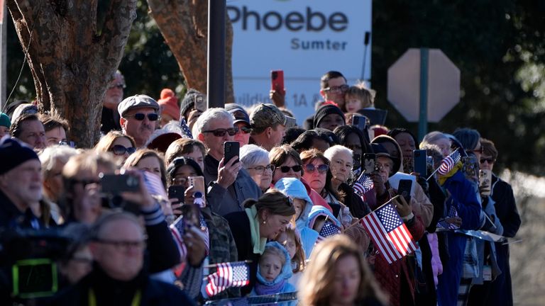 Crowds watch Jimmy Carter's hearse leaving Phoebe Sumter Medical Center in Americus, Georgia. Pic: AP