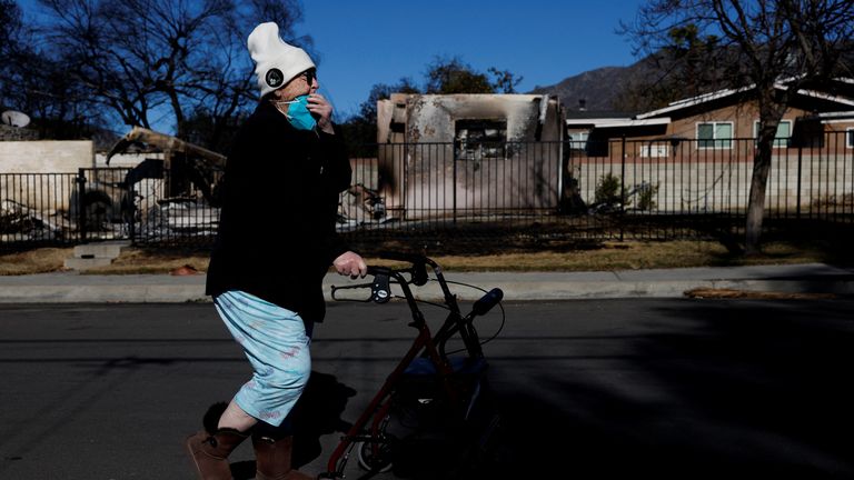 A woman walks past destroyed homes. Pic: Reuters