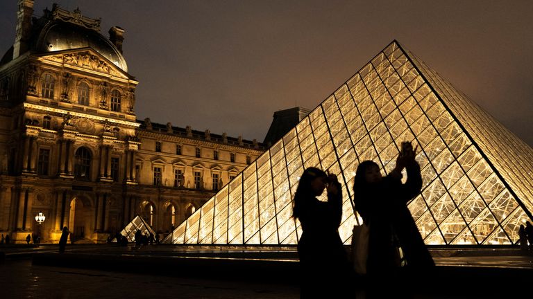 Tourists walk near the glass pyramid of the Louvre museum in Paris, France, January 24, 2025. REUTERS/Gonzalo Fuentes
