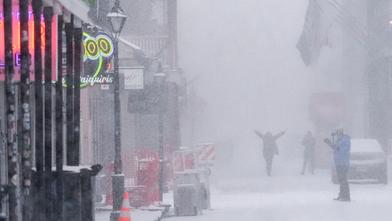 People walk around on Bourbon Street as snow falls in the French Quarter in New Orleans, Tuesday, Jan. 21, 2025. (AP Photo/Gerald Herbert)