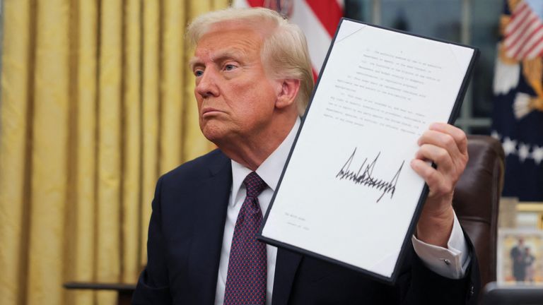 U.S. President Donald Trump holds a document on the day he issues executive orders and pardons for January 6 defendants in the Oval Office at the White House on Inauguration Day in Washington, U.S., January 20, 2025. REUTERS/Carlos Barria