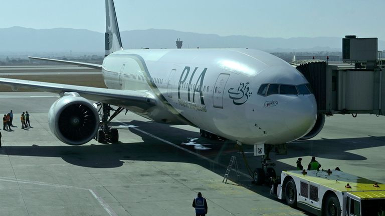 Ground staff work beside the state-run Pakistan International Airlines plane preparing to take-off for Paris after the airline resumes direct flights to Europe after EU lifted a four-year ban, at the Islamabad International Airport, in Islamabad, Pakistan, Friday, Jan. 10, 2025. (AP Photo)