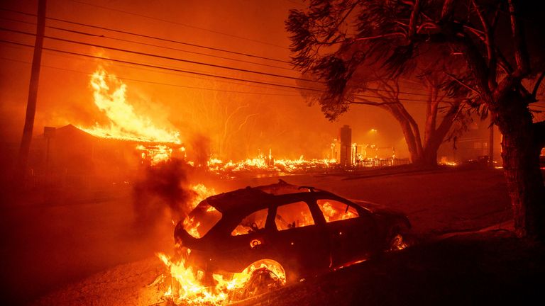 The Palisades Fire ravages vehicles and buildings in the Pacific Palisades neighborhood of Los Angeles, Tuesday, Jan. 7, 2025. (AP Photo/Ethan Swope)