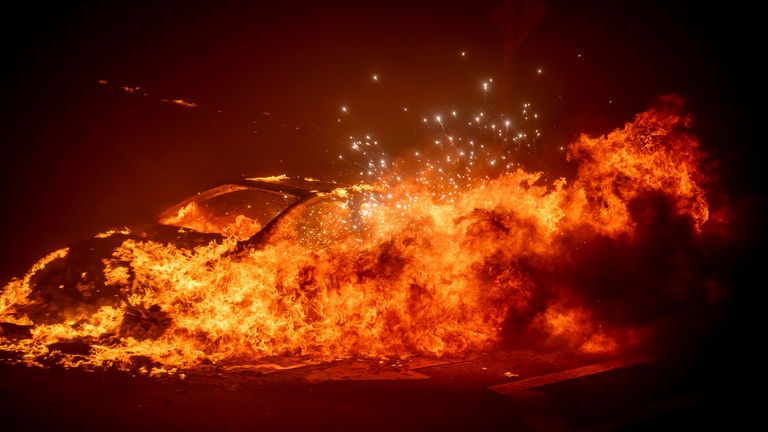 A vehicle burns as the Palisades Fire advances in the Pacific Palisades neighborhood of Los Angeles, Tuesday, Jan. 7, 2025. (AP Photo/Ethan Swope)