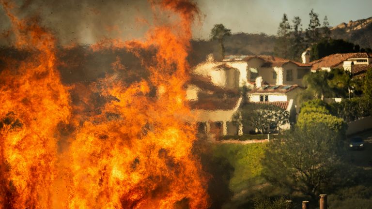 Flames rise as the Palisades Fire approaches homes in the Pacific Palisades neighborhood of Los Angeles, Tuesday, Jan. 7, 2025. (AP Photo/Ethan Swope)