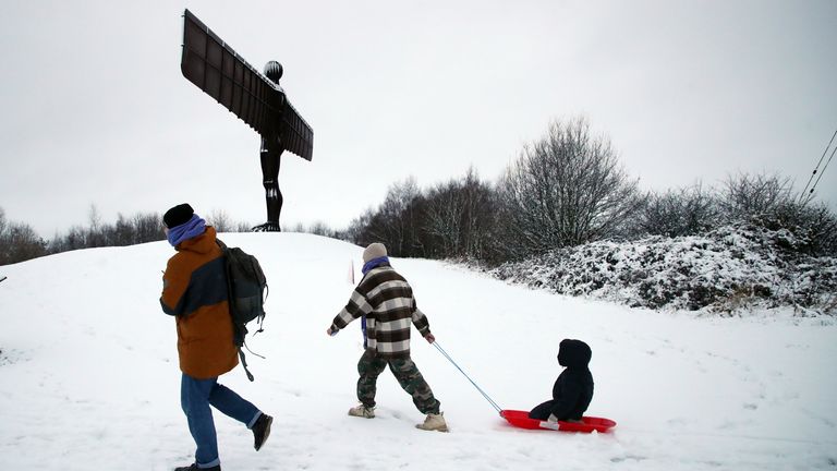 Lady pulling her child in a sled by the Angel of the North in Gateshead. Pic: AP