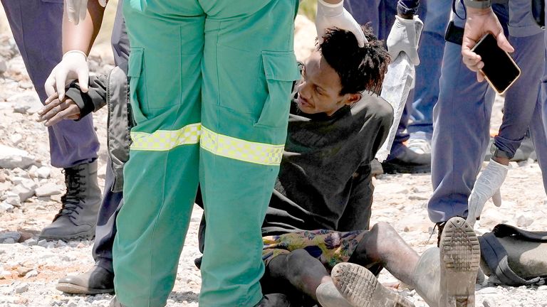 A miner is assisted by rescue workers after he was rescued from below ground in an abandoned gold mine in Stilfontein, South Africa, Tuesday, Jan. 14, 2025. (AP Photo/Themba Hadebe)