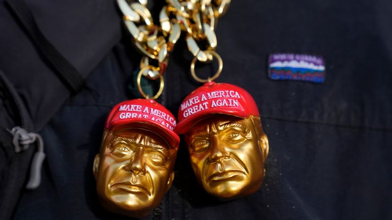 A merchandise vendor wears jewelry in the shape of President Donald Trump as he stands near Capitol One Arena in Washington.
Pic: AP