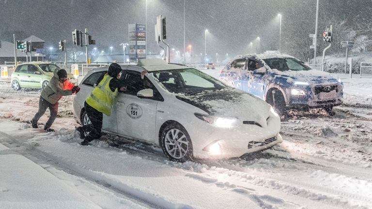 People help to push cars stuck in snow in Leeds, West Yorkshire. Pic: PA