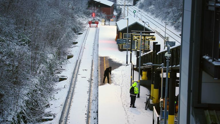 A worker clears snow from the platform at Hunt's Cross station in Liverpool. Pic: PA