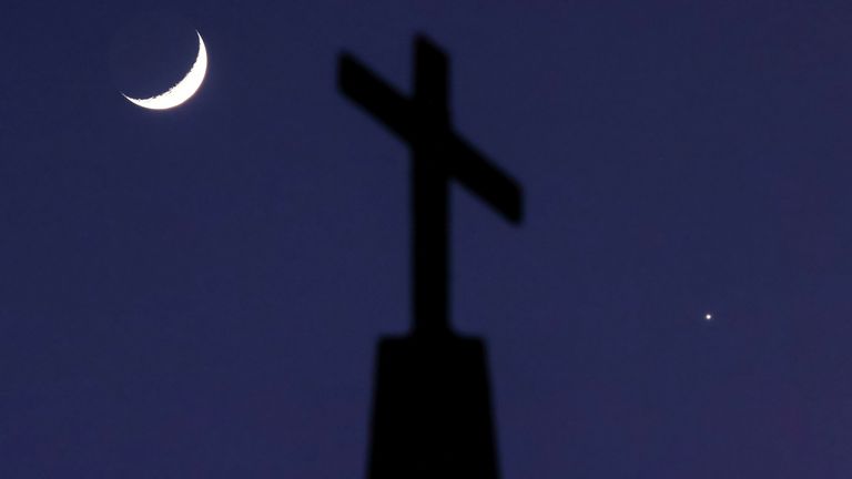 A crescent moon and the planet Venus straddle a cross on top of Quebec Baptist Church in Ellaville, Georgia, U.S. January 3, 2025. REUTERS/Sam Wolfe