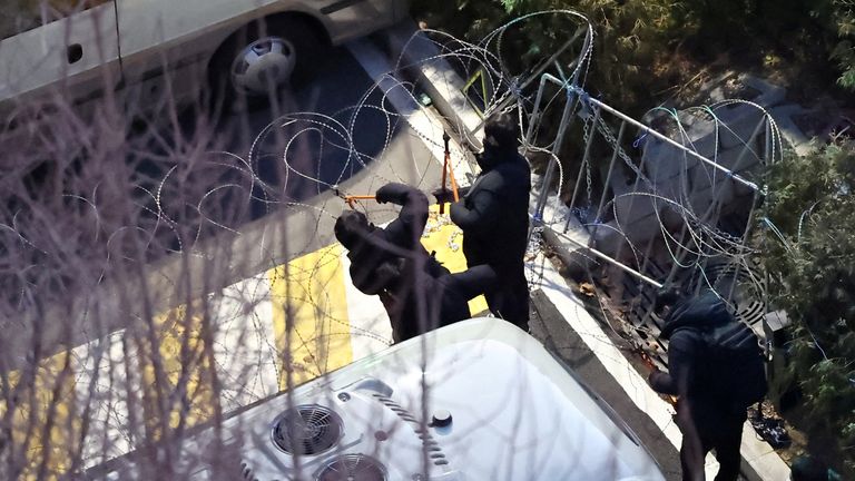 Police officers cut through a wire fence set up at the entrance to Yoon Suk Yeol's official residence.
Pic: Reuters