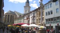 Numerous street cafes captured at the main square in the pedestrian area in Villach, Austria, 28 June 2008. The Trinity Column errected by way of thanks for the averted black plague is pictured in the foreground and the church spire of the parish church St Jacob in the back. The origin of the main square dates back to the 12th century. It is surrounded by patrician houses and inner yards of the renaissance. Pic: AP