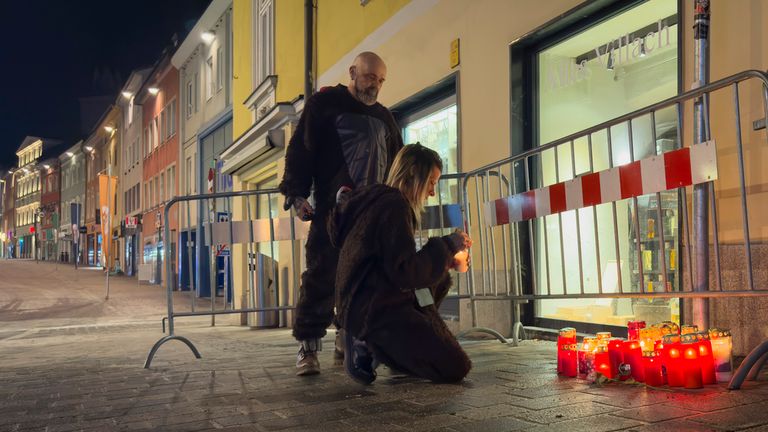 A person lights a candle at the site of a stabbing attack in Villach, Austria, Sunday, Feb. 16, 2025. (AP Photo/Darko Bandic)