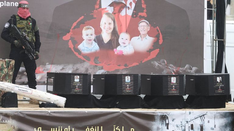 A Hamas militant stands on stage near coffins during the handover of deceased hostages Oded Lifschitz, Shiri Bibas and her two children Kfir and Ariel Bibas, seized during the deadly October 7, 2023 attack, to the Red Cross, as part of a ceasefire and hostages-prisoners swap deal between Hamas and Israel, in Khan Younis in the southern Gaza Strip, February 20, 2025. REUTERS/Ramadan Abed