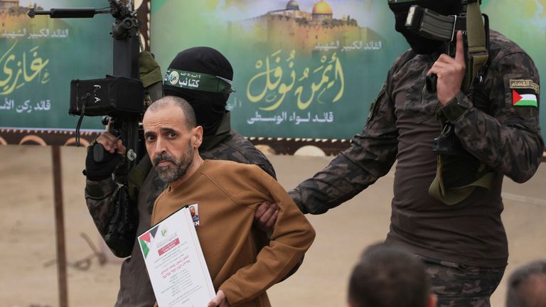 Israeli captive Eli Sharabi, who has been held hostage by Hamas in Gaza since October 7, 2023, is escorted by Hamas fighters before being handed over to the Red Cross in Deir al-Balah, central Gaza Strip, Saturday Feb. 8, 2025. (AP Photo/Abdel Kareem Hana)