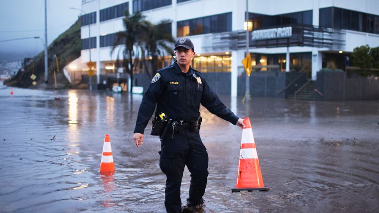 A police officer stands in a flooded intersection on Thursday in the Pacific Palisades. Pic: AP