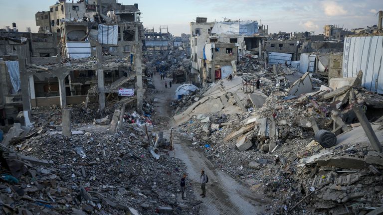 Palestinians walk in the destruction caused by Israel in Jabaliya.
Pic: AP/Abdel Kareem Hana