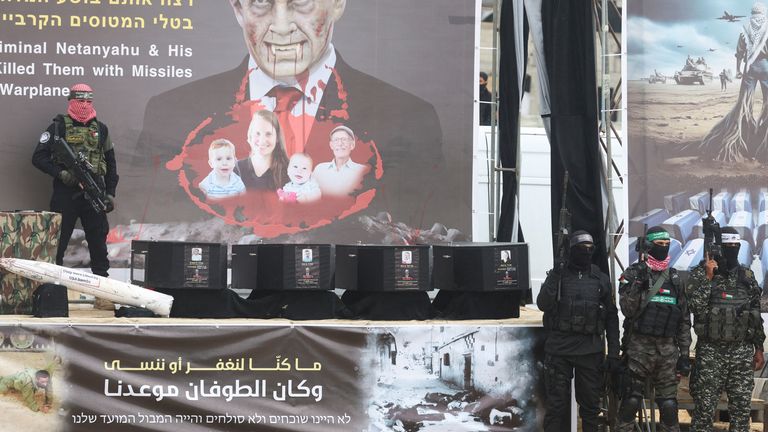 A Hamas militant stands on stage near coffins during the handover of deceased hostages Oded Lifschitz, Shiri Bibas and her two children Kfir and Ariel Bibas, seized during the deadly October 7, 2023 attack, to the Red Cross, as part of a ceasefire and hostages-prisoners swap deal between Hamas and Israel, in Khan Younis in the southern Gaza Strip, February 20, 2025. REUTERS/Ramadan Abed
