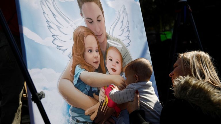 A woman holds a child up to a picture of the family. Pic: Reuters