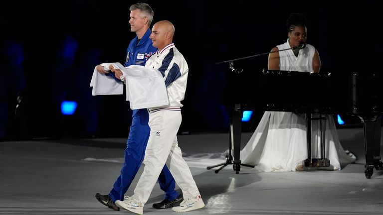 The Paralympic flag is brought on stage by John McFall (left) and Damien Seguin as the Paralympic Anthem is performed by Luan Pommier during the opening ceremony of the Paris 2024 Olympic Games at the Place de la Concorde. Picture date: Wednesday August 28, 2024. PA Photo. See PA story PARALYMPICS Ceremony. Photo credit should read: Andrew Matthews/PA Wire...RESTRICTIONS: Use subject to restrictions. Editorial use only, no commercial use without prior consent from rights holder.