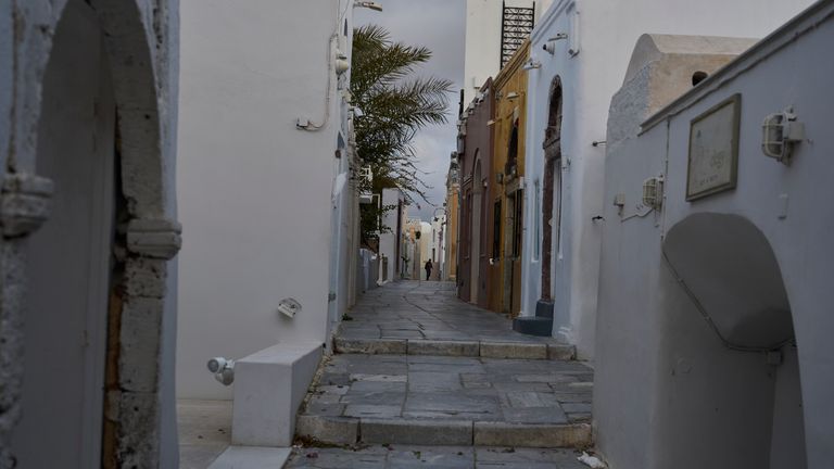 A man walks on an empty street in the town of Oia on the earthquake-struck island of Santorini, Greece, Tuesday, Feb. 4, 2025. (AP Photo/Petros Giannakouris)