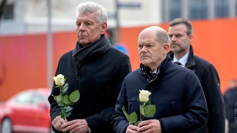 German Chancellor Olaf Scholz, right, brings a flower to the site where a car crashed into a Thursday Ver.di labor union demonstration in Munich, on Saturday, Feb. 15, 2025. Pic: AP