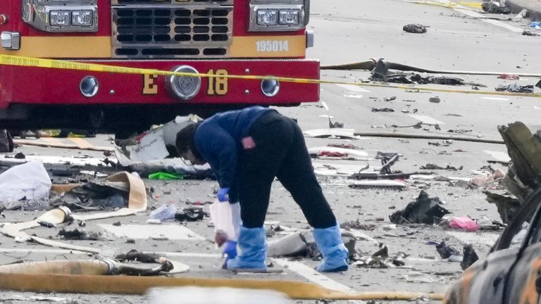 An investigator works the scene after a small plane crashed in Philadelphia. Pic: AP/Matt Rourke