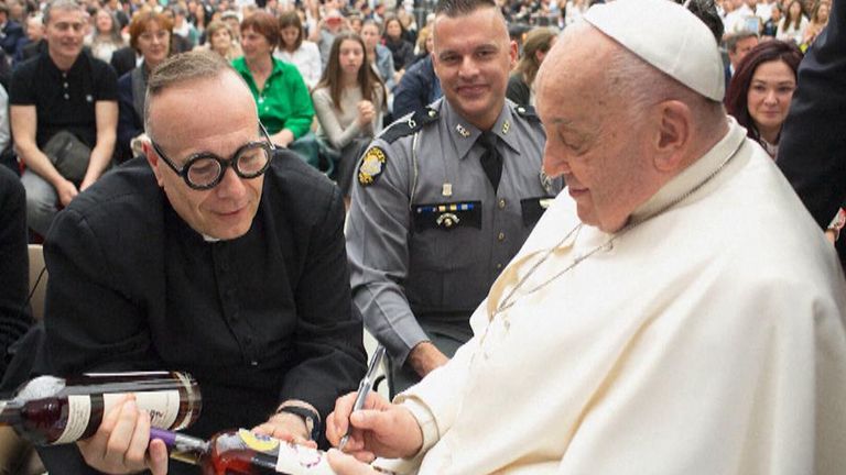 Pope Francis signs a bottle of bourbon. Pic: Vatican Media