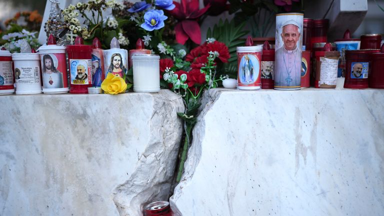 Candles and flowers are placed on a statue of Pope John Paul II in front of the Agostino Gemelli Polyclinic, in Rome, Thursday, Feb. 20, 2025, where the Pontiff is hospitalized since Friday, Feb. 14.(AP Photo/Alessandra Tarantino)