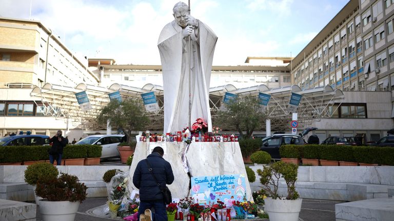 A man prays next to the statue of late Pope John Paul II outside Gemelli Hospital, where Pope Francis is admitted for treatment, in Rome, Italy, February 28, 2025. REUTERS/Alkis Konstantinidis