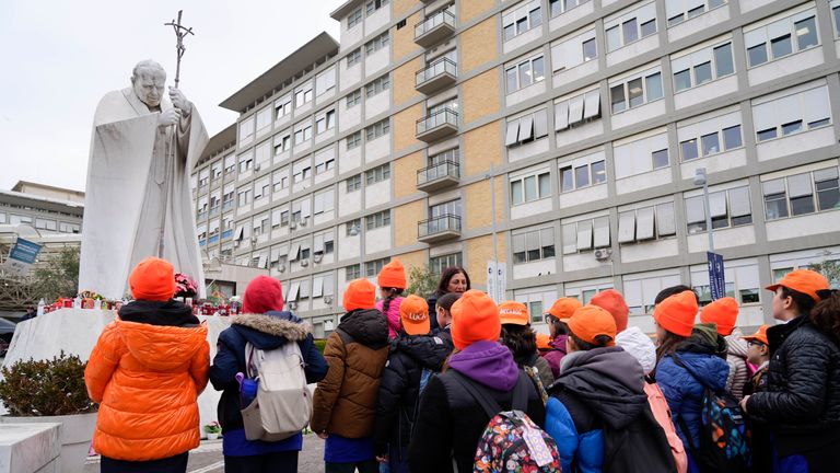 A group of children from a primary school pray for Pope Francis in front of the statue Pope John Paul II outside Agostino Gemelli Polyclinic in Rome, Wednesday, Feb. 19, 2025, where the Pontiff is hospitalized since Friday, Feb. 14. (AP Photo/Gregorio Borgia)