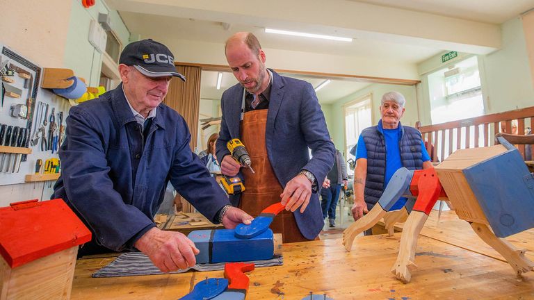 Prince William, The Duke of Rothesay stands alongside Alex Campbell and Derek Stewart who show him how to make a ''Tree-Hugger'' at the Carnoustie and Monifieth Men's Shed.
Pic: Reuters