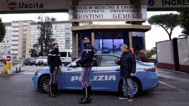 Police members stand next to a car outside the Gemelli Hospital where Pope Francis has gone to continue treatment for ongoing bronchitis in Rome, Italy, February 14, 2025. REUTERS/Remo Casilli