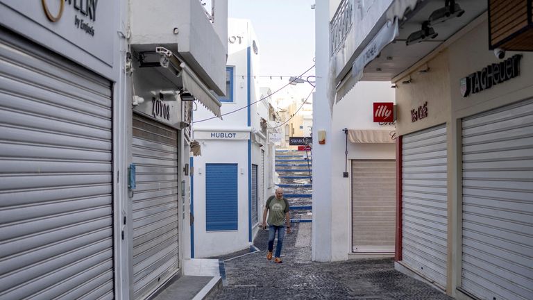 A man walks between closed tourist shops in Santorini.
Pic: Reuters