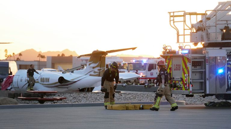 Firefighters work around the site of a crashed Learjet at Scottsdale Airport after it collided with a parked plane Monday, Feb. 10, 2025, in Scottsdale, Ariz. (AP Photo/Ross D. Franklin)