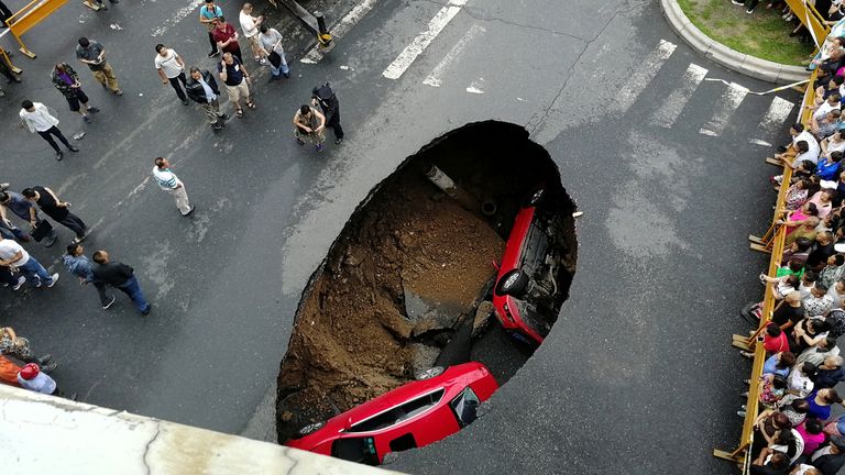 People gather near the scene where two vehicles have fallen into a sinkhole on a street in Harbin, Heilongjiang province, China August 4, 2018. Picture taken August 4, 2018. REUTERS/Stringer ATTENTION EDITORS - THIS IMAGE WAS PROVIDED BY A THIRD PARTY. CHINA OUT.