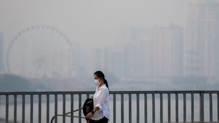 A woman wearing a face masks walks through Bangkok.
Pic: Reuters/Athit Perawongmetha