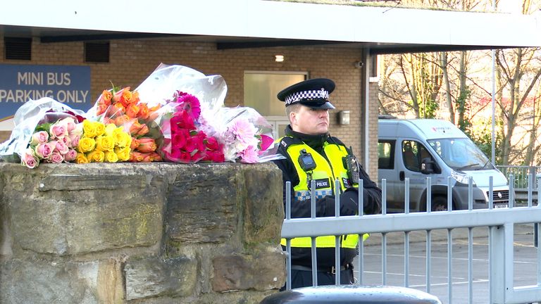 A police office stands near tributes outside the All Saints Catholic High School, on Granville Road in Sheffield. Pic: PA