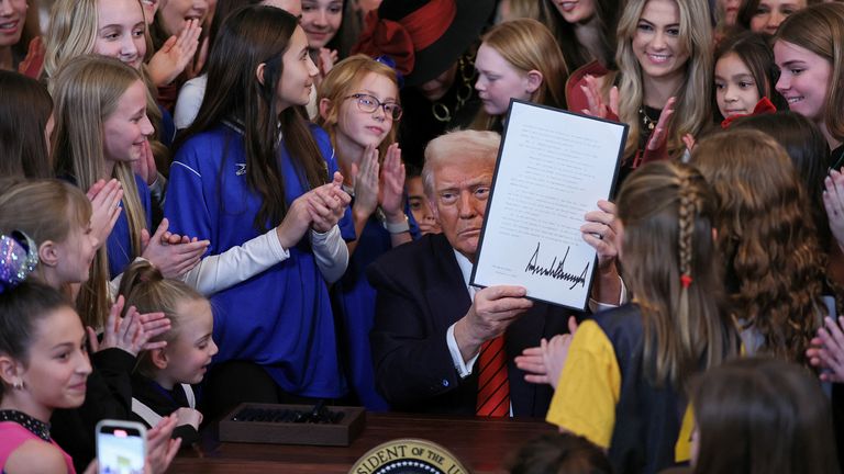 Donald Trump holds up a signed executive order banning transgender girls and women from participating in women's sports. Pic: Reuters